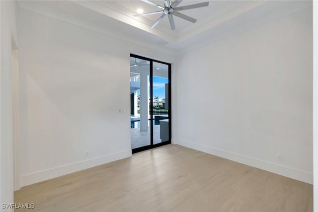 unfurnished room with a tray ceiling, recessed lighting, ceiling fan, light wood-type flooring, and baseboards