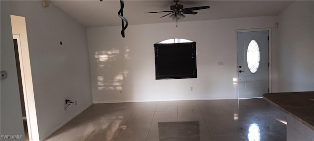 tiled foyer with baseboards and ceiling fan