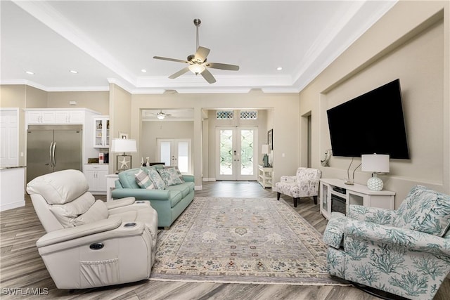 living room featuring hardwood / wood-style flooring, a raised ceiling, crown molding, and french doors