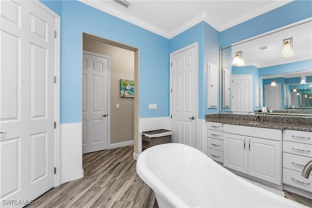 bathroom with ornamental molding, vanity, a washtub, and hardwood / wood-style floors