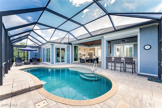 view of pool with a patio area, an outdoor bar, ceiling fan, and glass enclosure