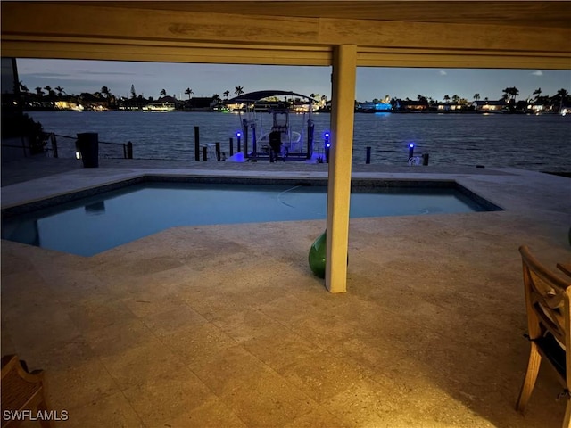 pool at dusk with a patio and a water view