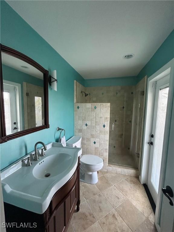 bathroom featuring toilet, a shower with shower door, and vanity