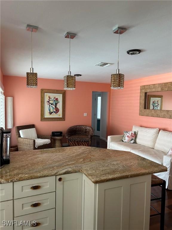 kitchen featuring decorative light fixtures, light stone counters, and a wealth of natural light