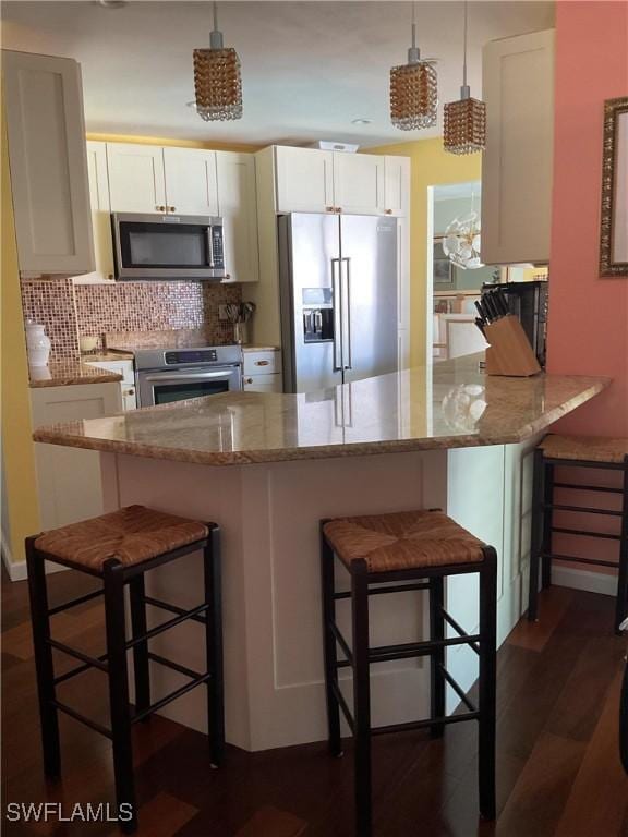 kitchen with white cabinetry, hanging light fixtures, a kitchen bar, and stainless steel appliances