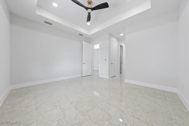 unfurnished bedroom with a tray ceiling and ceiling fan