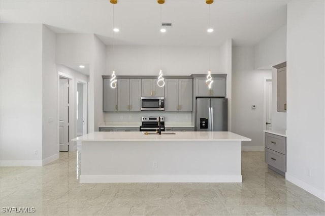kitchen featuring sink, gray cabinetry, hanging light fixtures, a center island with sink, and appliances with stainless steel finishes