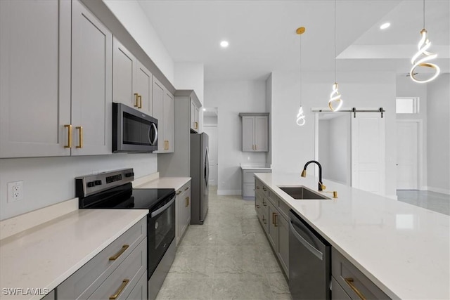 kitchen with stainless steel appliances, a barn door, sink, and decorative light fixtures