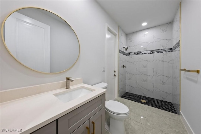 bathroom with tiled shower, vanity, and toilet