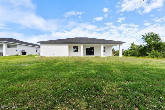 back of property with central AC and a lawn