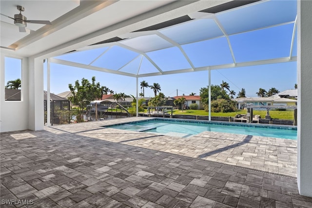 view of swimming pool featuring a patio, ceiling fan, and glass enclosure