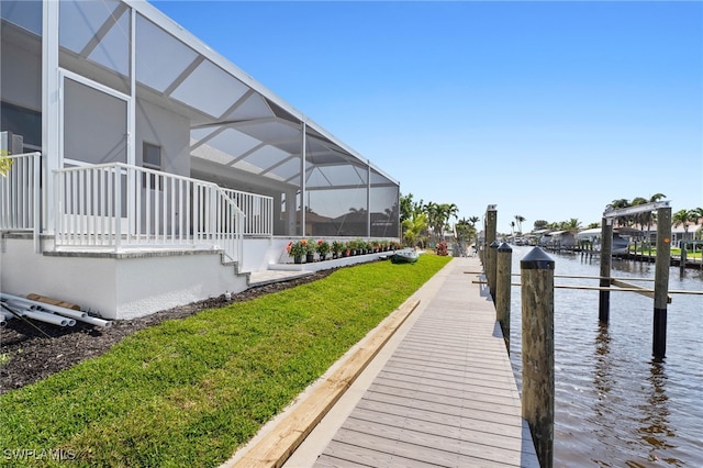 view of dock featuring a lanai, a water view, and a yard