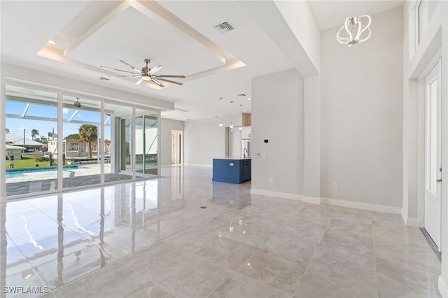 unfurnished room with ceiling fan with notable chandelier and a raised ceiling