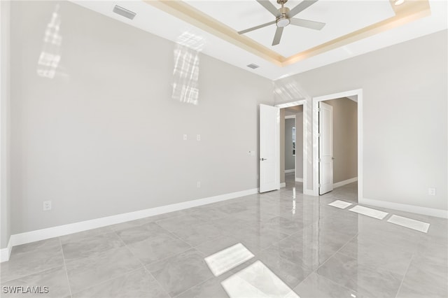 unfurnished bedroom with ceiling fan and a raised ceiling