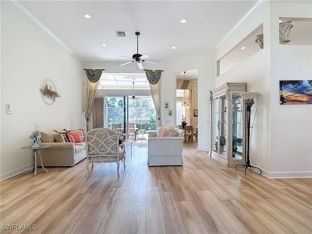 living room featuring baseboards, light wood finished floors, visible vents, and crown molding