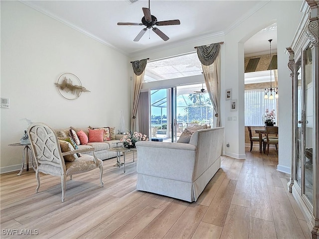 living room featuring light wood finished floors, baseboards, crown molding, and ceiling fan with notable chandelier