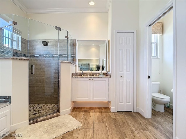 bathroom featuring a stall shower, crown molding, vanity, and toilet