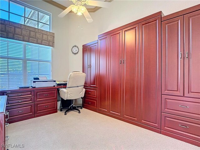 carpeted office with ornamental molding, a towering ceiling, and a ceiling fan