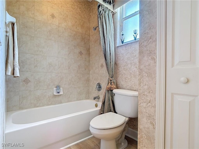 bathroom featuring shower / bathtub combination with curtain, toilet, wood finished floors, baseboards, and wallpapered walls