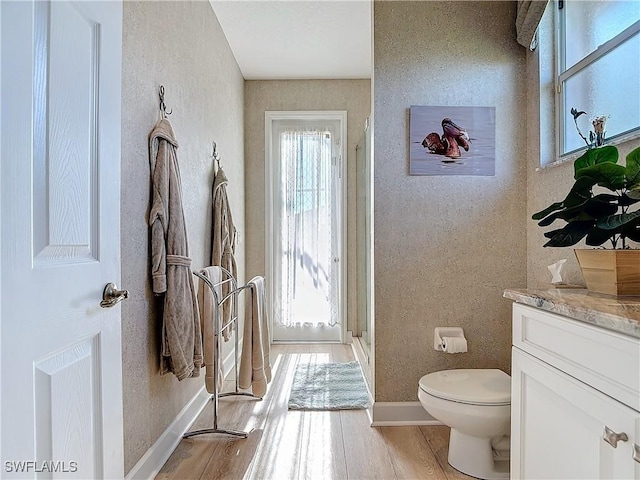 bathroom with a textured wall, toilet, wood finished floors, vanity, and a shower stall