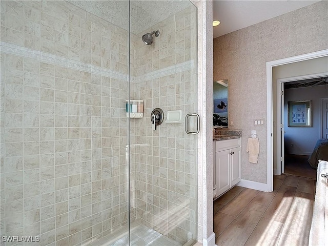 bathroom with a shower stall, baseboards, wood finished floors, and vanity