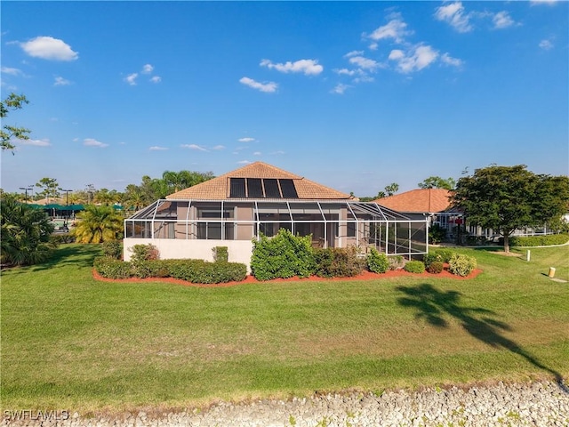 back of property with glass enclosure and a lawn