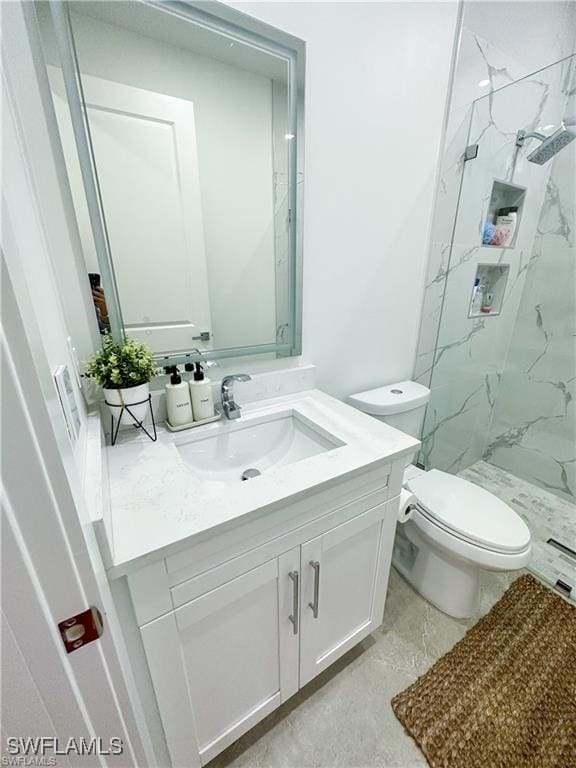 bathroom featuring vanity, toilet, and a tile shower