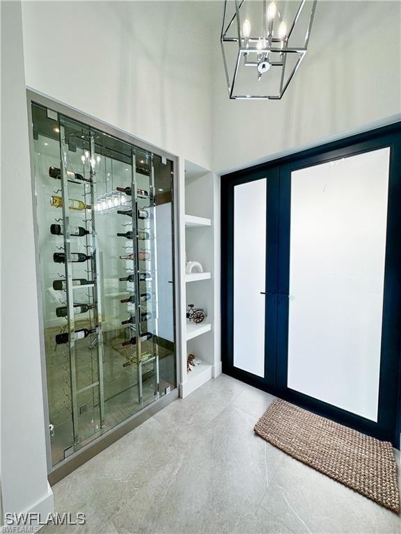 wine area featuring french doors, a chandelier, and a high ceiling