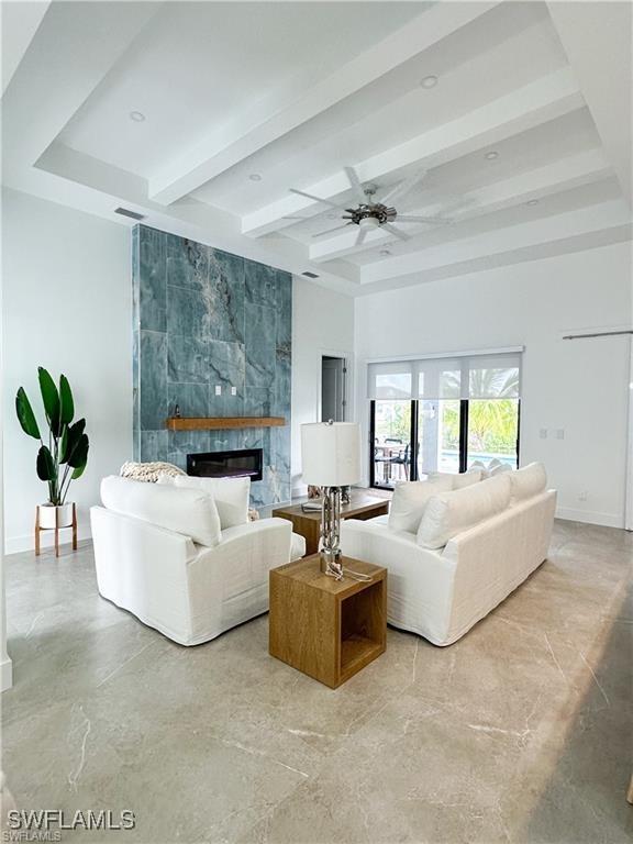 living room with beam ceiling, a large fireplace, and ceiling fan