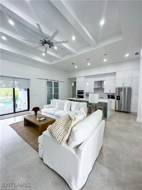 living room featuring beamed ceiling, a barn door, and ceiling fan