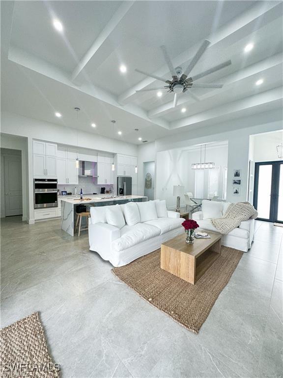 living room featuring beamed ceiling and ceiling fan