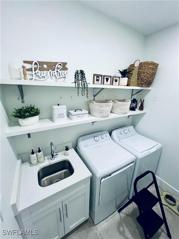 clothes washing area with washer and dryer, sink, and cabinets