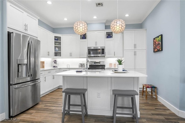 kitchen featuring visible vents, an island with sink, glass insert cabinets, stainless steel appliances, and light countertops