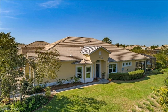 view of front of property featuring a tiled roof, a front lawn, and stucco siding