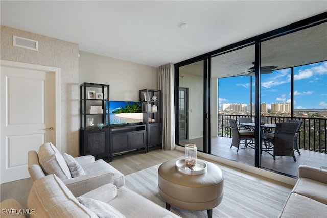 living room featuring ceiling fan, floor to ceiling windows, and light hardwood / wood-style flooring