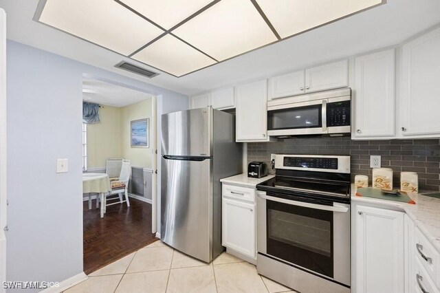 2228 Poinciana Dr, Naples, FL 34105 - kitchen with light countertops, stainless steel appliances, backsplash, visible vents, and white cabinets