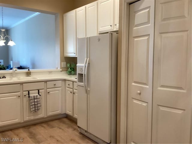 8528 Brittania Dr, Fort Myers, FL 33912 - kitchen with sink, white cabinetry, light wood-type flooring, ornamental molding, and white refrigerator with ice dispenser