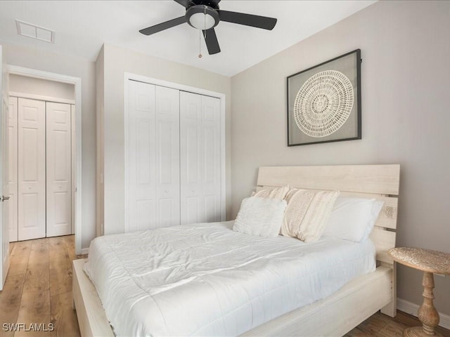 bedroom with baseboards, a closet, visible vents, and wood finished floors