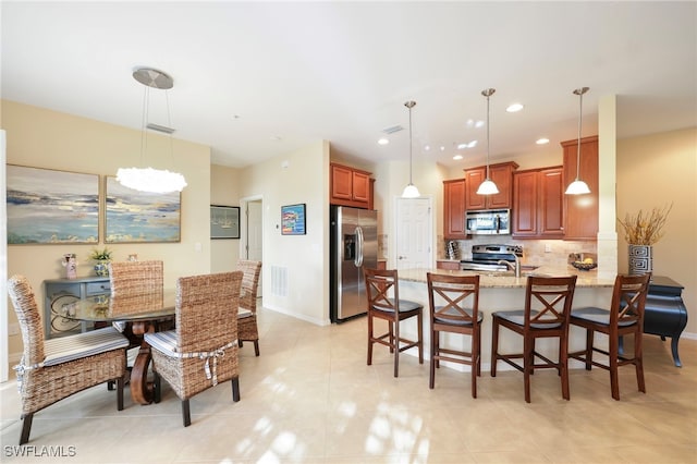kitchen with stainless steel appliances, decorative light fixtures, a peninsula, and a kitchen bar