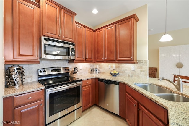 kitchen featuring decorative light fixtures, light tile patterned floors, appliances with stainless steel finishes, a sink, and light stone countertops
