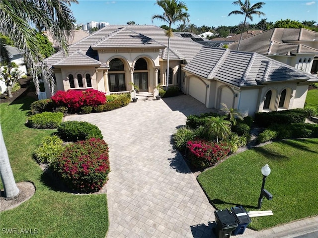 mediterranean / spanish house with a garage, a tile roof, and stucco siding