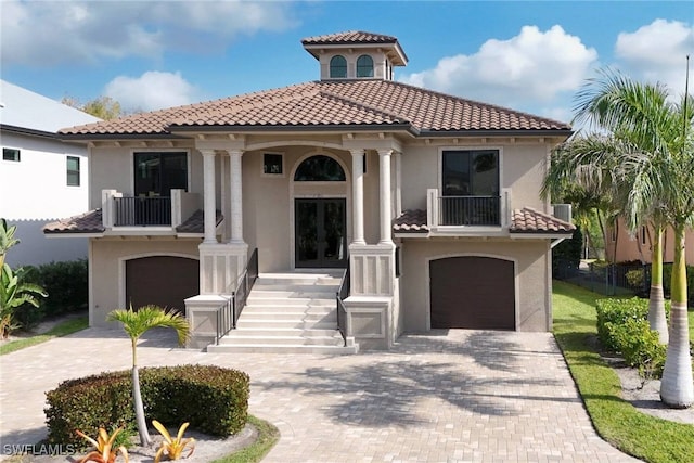 mediterranean / spanish house featuring a balcony, an attached garage, decorative driveway, and stucco siding