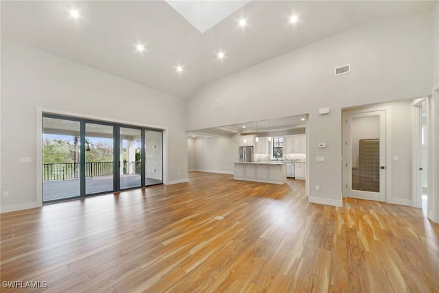 unfurnished living room with visible vents, high vaulted ceiling, light wood-style flooring, and baseboards