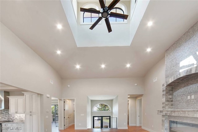 living room featuring a large fireplace, a high ceiling, a ceiling fan, and recessed lighting