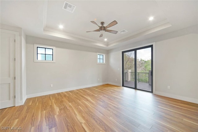 unfurnished room featuring light wood-type flooring, a raised ceiling, visible vents, and baseboards