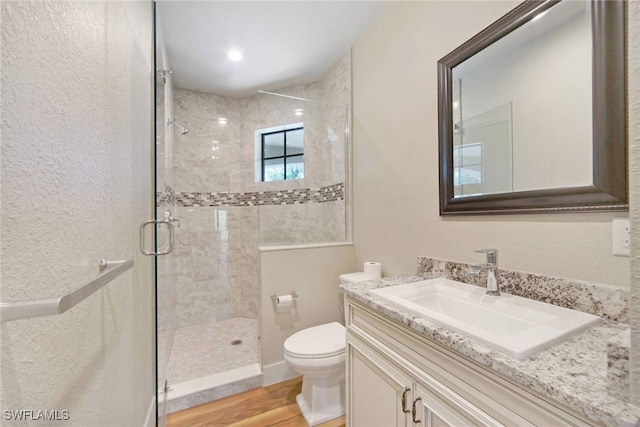 full bathroom featuring toilet, a shower stall, vanity, and wood finished floors