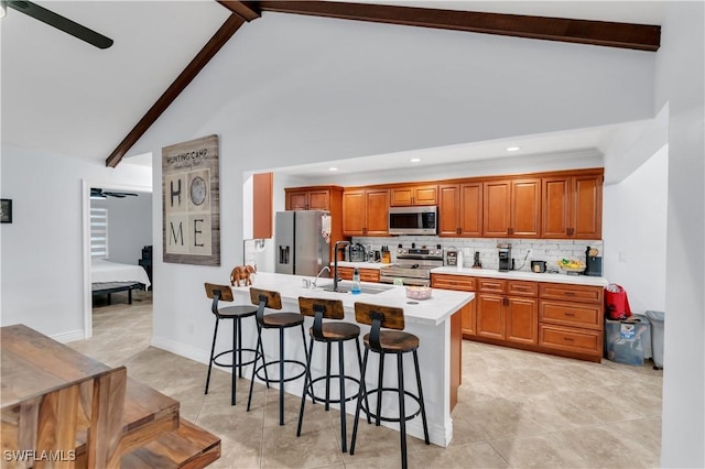 kitchen with a breakfast bar, light countertops, appliances with stainless steel finishes, a ceiling fan, and beamed ceiling