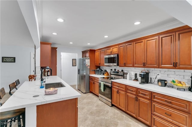 kitchen featuring backsplash, appliances with stainless steel finishes, a kitchen breakfast bar, and a sink