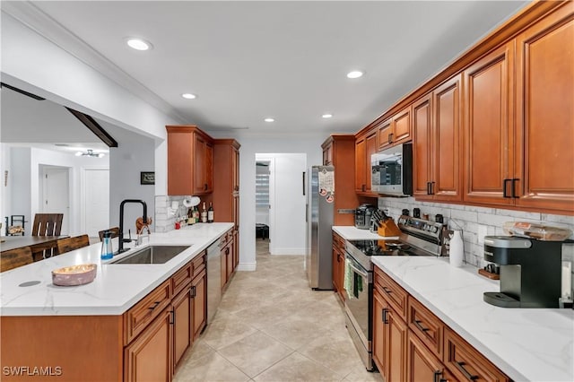 kitchen featuring brown cabinetry, light stone counters, appliances with stainless steel finishes, a sink, and backsplash