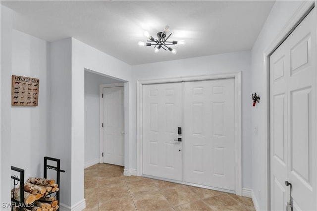 foyer with light tile patterned flooring, a notable chandelier, and baseboards